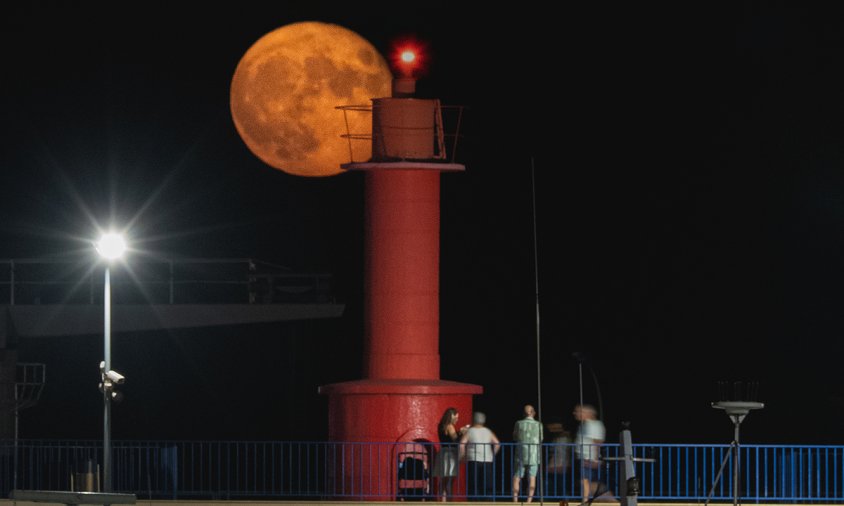 Lluna plena com a teló de fons del far vermell del port cambrilenc