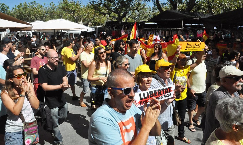 El pas dels manifestants cridant per la llibertat dels presos polítics i al fons, un grupet unionista mostrant banderes espanyoles