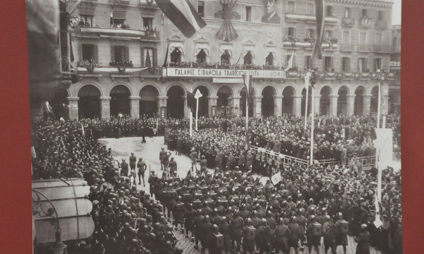 Una de les fotos de l'exposició en què es veu una desfilada militar i falangista a la plaça del Prim de Reus en motiu del primer aniversari del final de la Guerra Civil