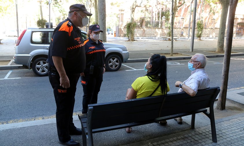Dos voluntaris de Protecció Civil controlant l'ús de mascareta entre dos veïns de Reus asseguts en un banc del passeig Sunyer, el passat agost
