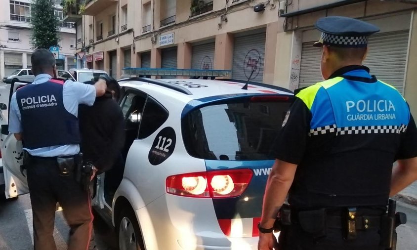 Imatge d'un agent dels Mossos introduïnt un detingut en un vehicle policial, amb un agent de la Guàrdia Urbana de Reus en primer terme
