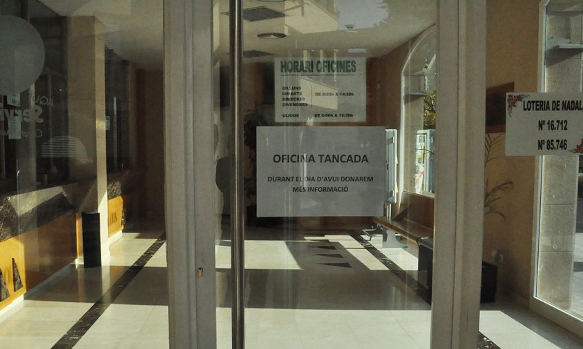 Porta de l'oficina de la secció de crèdit de la Cooperativa Agrícola amb el cartell que es va col·locar anunciant el tancament, el 22 de desembre de 2015