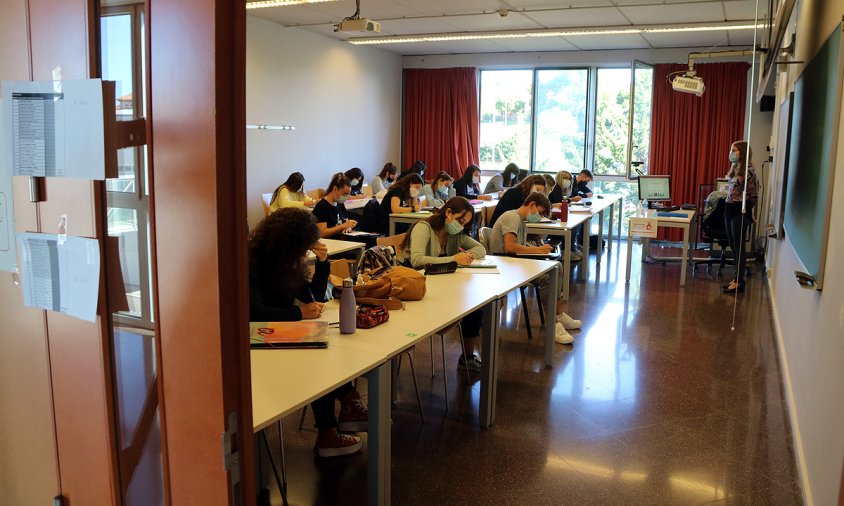 Imatge d'una aula de la URV, vista des de fora, amb alumnes fent classe amb mascareta en el primer dia del curs, el passat 28 de setembre