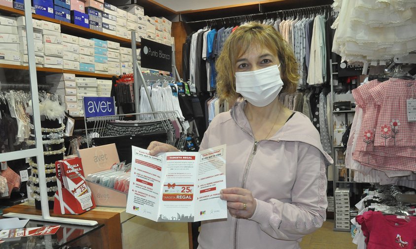 Núria Torres, propietària de la botiga Corseteria Nuria, mostrant les targetes regal de la Unió de Botiguers
