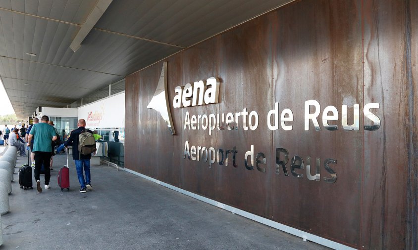 Imatge de la façana principal de l'aeroport de Reus i turistes amb maletes accedint a la terminal de sortides
