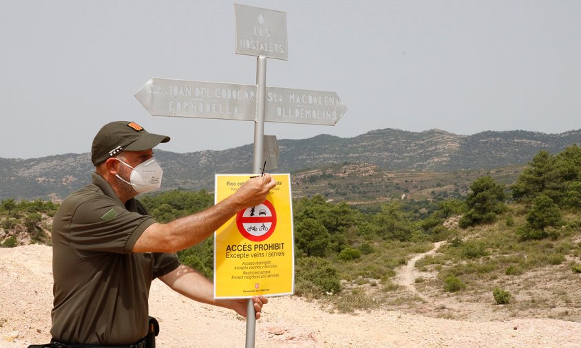 Una agent rural penja un cartell advertint de la restricció d'accés al Parc Natural de la Serra del Montsant