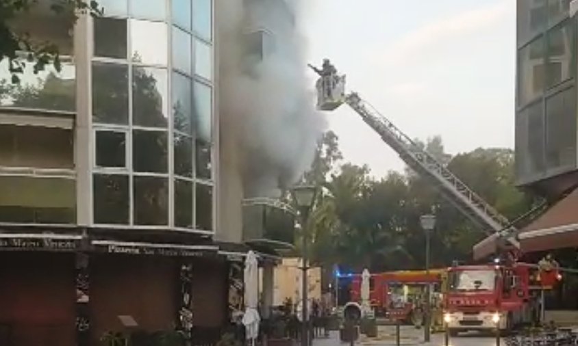 Edifici sinistrat amb el fum que sortia i els bombers actuant