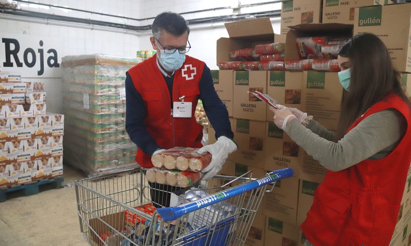 Imatge de dos voluntaris de Creu Roja Tarragona omplint el carro d'aliments per una persona en situació de vulnerabilitat