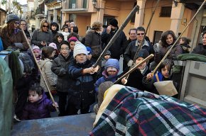 Desenes de nens i nenes fan cagar el tió amb els escoltes de l'Agrupació Gent de Mar