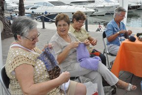 Un grup de dones es reuneix per a fer mitja, al port, dins de projecte solidari La bufanda de la iaia