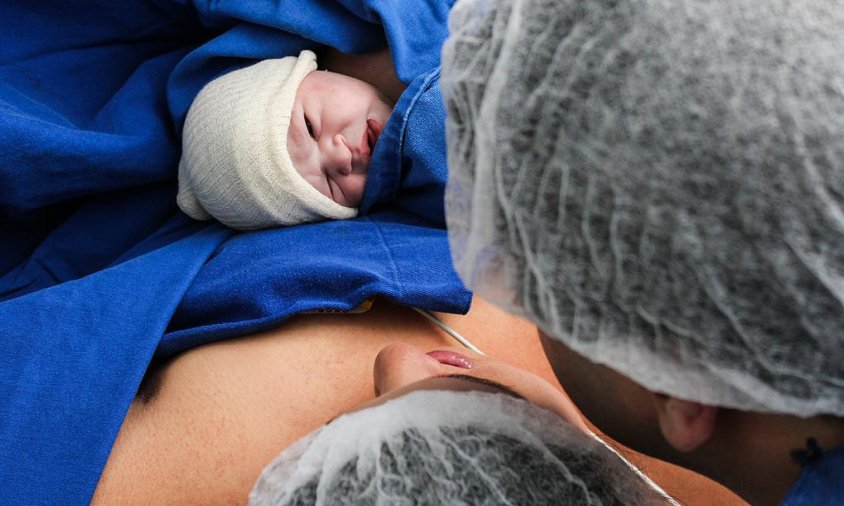 Imatge d'una mare i un pare agafant el seu nadó acabat de néixer