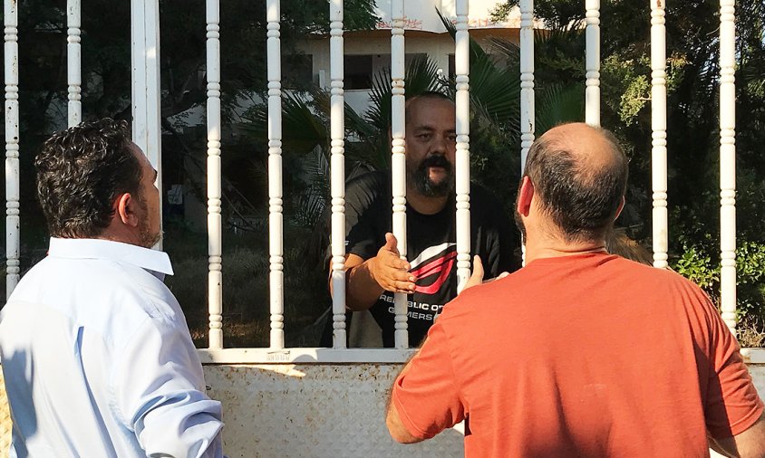 Jorge Fernández, un dels ocupants de l'edifici, parla amb dos veïns a la porta del jardí de l'antiga residència Montemar, aquesta tarda