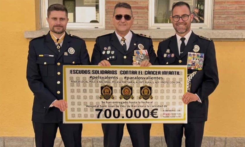 Imatge de tres agents de la policia implicats en la campanya mostrant el xec simbòlic de 700.000 euros
