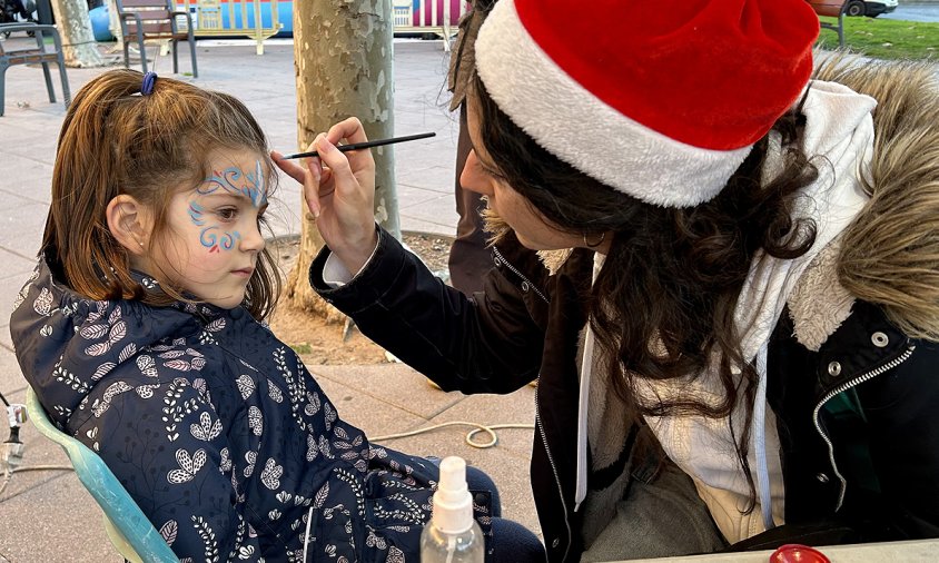 La maquilladora pinta la cara a una de les nenes que va participar al taller fet a la plaça Creu de la Missió