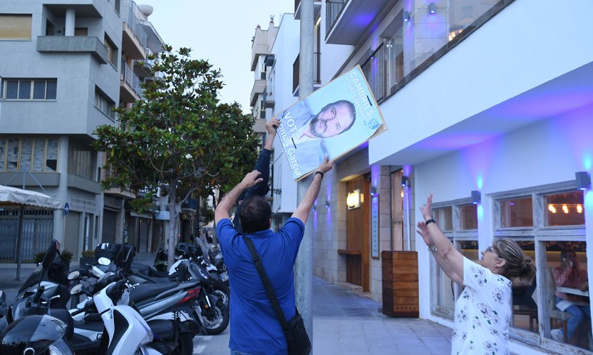 El cap de llista de l'ADN, Tomás Garcia, acompanyat de dues persones despenjant un cartell al port, ahir al vespre