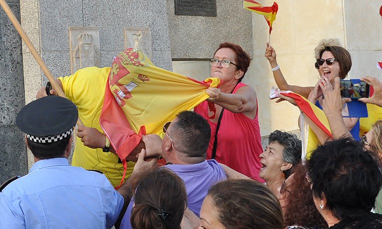 Una dona estira el cap d'un independentista amb la seva bandera espanyola