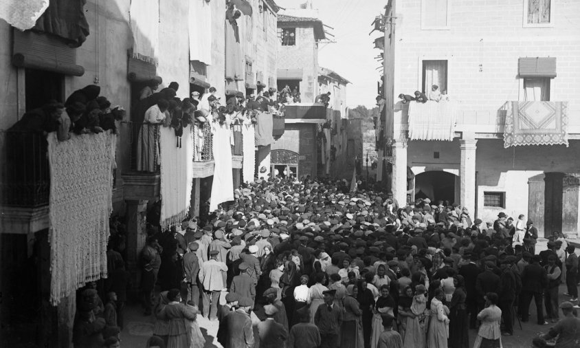 Gernació aplegada a la plaça de la Vila amb motiu de l’homenatge al doctor Gimbernat. Destaquen els balcons endomassats i plens de persones. Al final del carrer de Gimbernat, s’aprecia la torre del Biel.