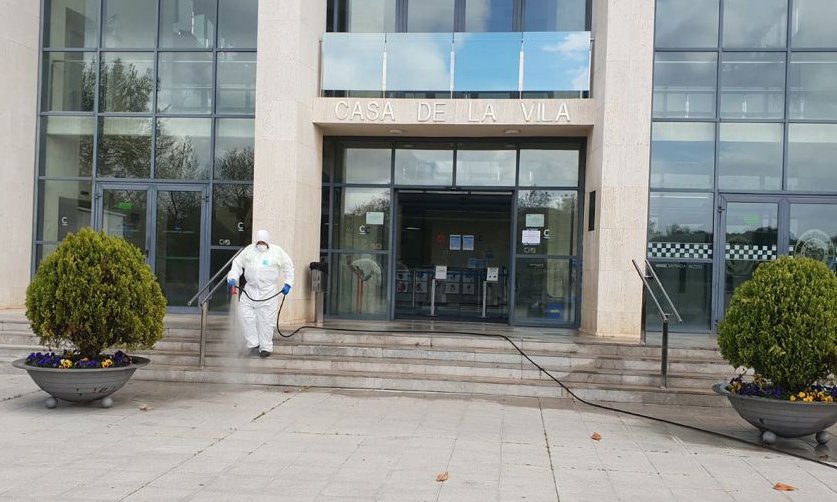 Image d'un opérerai fent tasques de neteja i desinfecció a l'entrada de l'edifici de l'Ajuntament