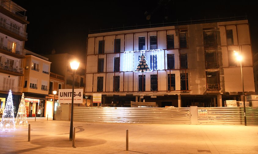 Imatge de la plaça del Pòsit amb les llums de l'arbre a la façana de l'edifici de l'hotel en obres