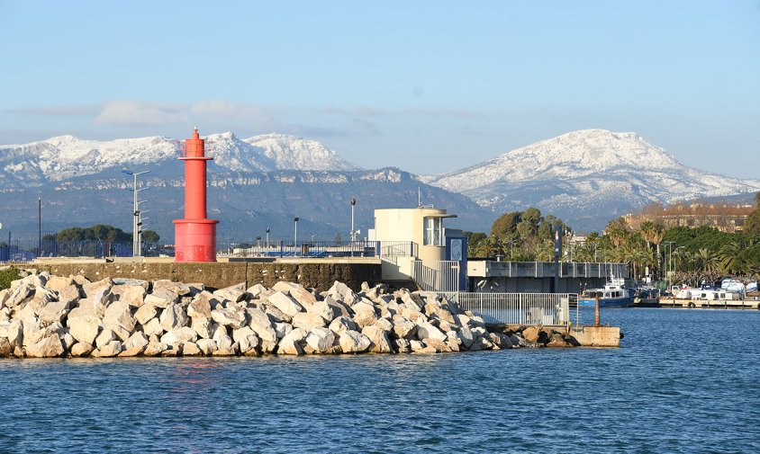 Far vermell del port de Cambrils amb la serra de Llaveria i la Mola de Colldejou nevades, al darrera