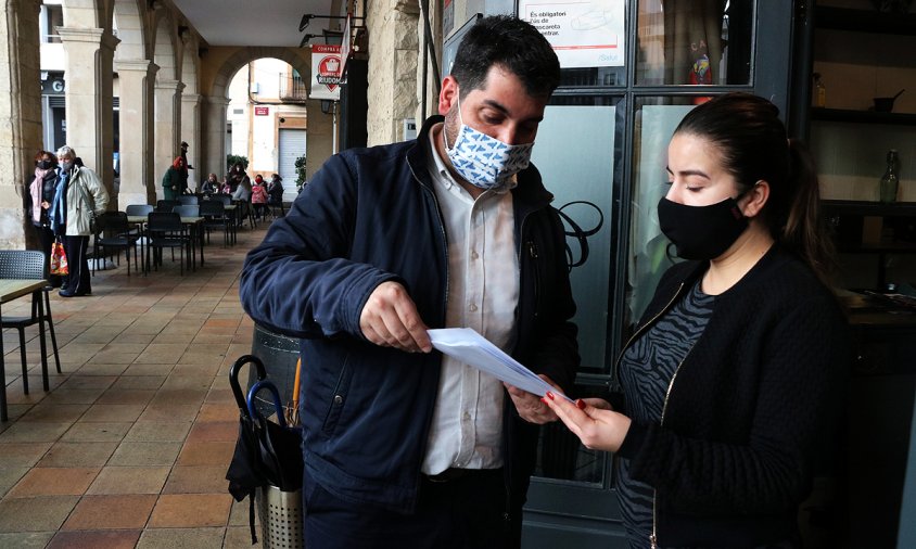 L'alcalde de Riudoms, Sergi Pedret, explicant la iniciativa 'Fes que destaqui' a la treballadora d'un bar del poble, el passat 18 de desembre