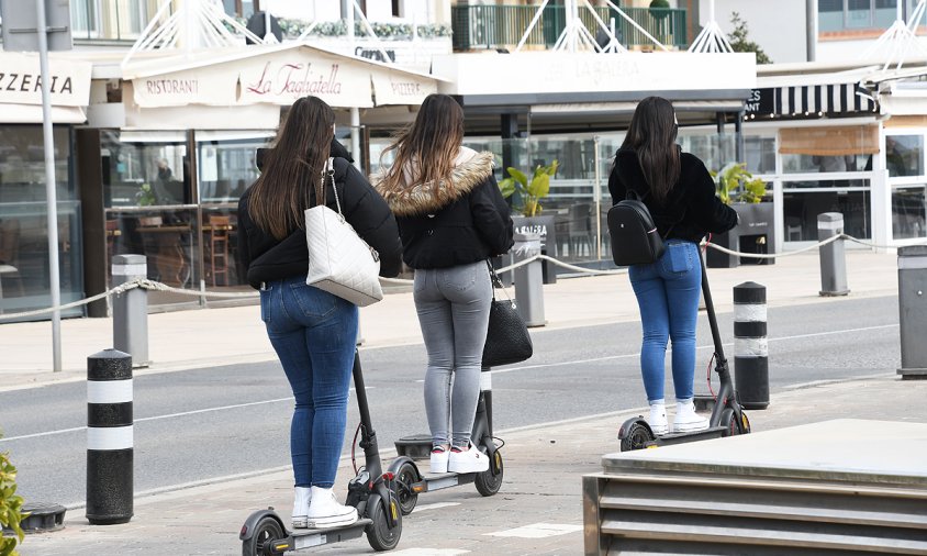 Tres persones dalt de patinets al carril bici de la façana del Port