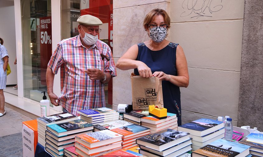 Imatge d'un client comprant un llibre en la parada de la llibreria Gaudí de Reus en el Sant Jordi d'estiu, el passat juliol