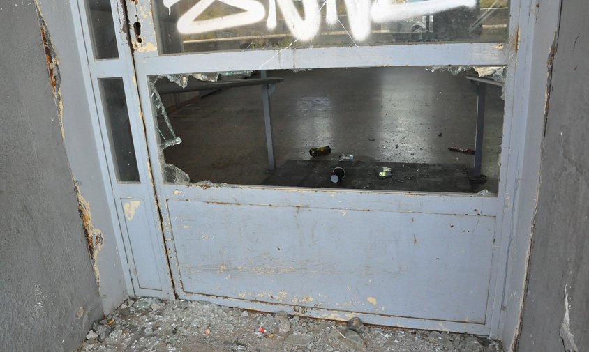 Imatge del vidre de la porta xafat i deixalles a l'interior de l'antiga estació
