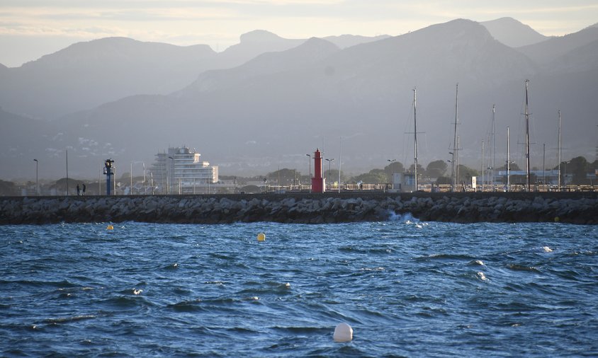 Platja del Regueral amb el far vermell del port al fons