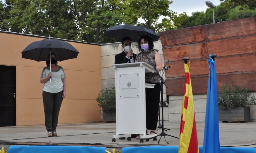 Un moment dels parlaments a càrrec de Rosa M. Abelló, amb l'alcaldessa al darrere i el director de Ràdio Cambrils, Adrià Muñoz, subjectant-li el paraigües
